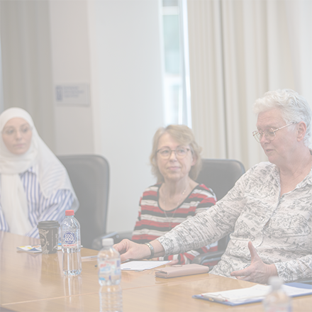 Three women sitting at a board room table.